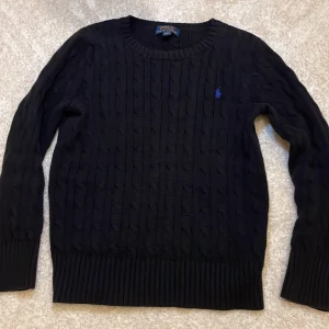 Kabelstickad Ralph lauren tröja - Säljer denna sjukt snygga Kabelstickad Ralph lauren tröja i svart pga av växt ut den. Skick:9,5/10 ,inga defekter alls sjukt bra skick. Denna är perfekt till hösten och har använts fåtal gånger. Hör av dig om några frågor.