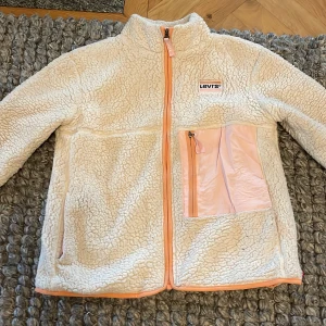 Levis teddyjacka vit - Säljer min Levis teddy-fleece pga för liten. Den har inga defekter. Mjukt material på utsidan. Bra vårjacka.