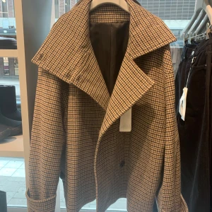 Rutig kappa från Arket  - Säljer denna populära höst kappa från Arket då jag har alldeles för många höstjackor! Från förra årets kolllektion så finns ej kvar att köpa längre. Sparsamt använd därav fint skick, i storlek 38.