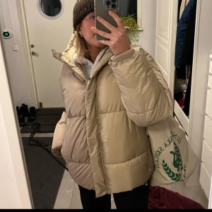 Beige vinterjacka - En skutsnyg varm gosig pufferjacka från monki använd sparsamt under en vinter. Lite halvt glansig och supervarm!