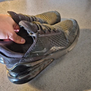 Nike Air Max 270 - Storlek 43, väl använda, skick 6.5/10. Bild 3 och 4 visar lilla hålet. Man kan ta en svart tygremsa och limma fast innefrån skon om man vill. Men jag brukar ha svarta strumpor så syns inte.