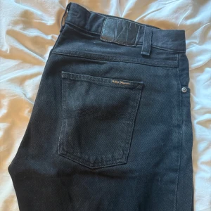 Nudie, Gritty Jackson - Svarta Nudie, Gritty Jackson i storlek W32L34.  Skick 8/10. Nypris 1600kr.  Hör av dig om du vill ha fler bilder!