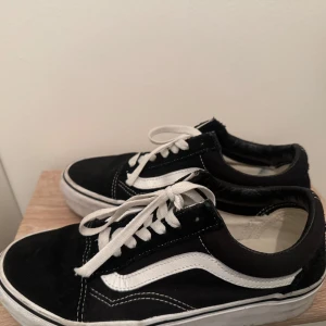 Svarta sneakers från Vans - I jättebra skick. 38EU. Säljer ett par klassiska svarta Vans sneakers med vit sula och snörning. Skorna har den ikoniska vita sidostripen och är perfekta för en avslappnad stil.