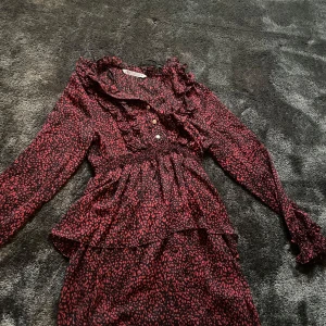 Svart och röd klänning från Zara - Snygg svart och röd klänning från Zara med ett leopardmönster. Klänningen har långa ärmar och volangdetaljer vid halsen och ärmsluten. Perfekt för en trendig look! Säljer pgr av att jag inte tycker om hur den sitter på mej❤️💕skriv för fler bilder 💕❤️💕