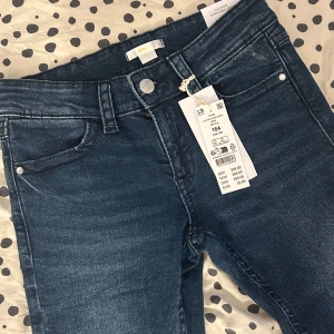 Blå low bootcut jeans från Gina Tricot - Snygga blå jeans med låg midja och broderade detaljer från Gina. Modellen är low boot och har klassiska femficksdesign med knappar. Perfekta för en avslappnad stil. Helt oanvända!☺️
