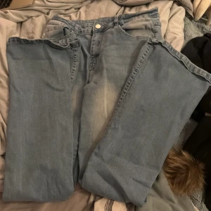 Ljusblå jeans med broderad detalj - Snygga ljusblå jeans med en broderad detalj på bakfickan. De har en klassisk femficksdesign och knappgylf. Perfekta för en avslappnad stil.