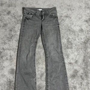 Grå bootcut jeans - Snygga grå bootcut jeans med klassisk femficksdesign och knappgylf. Perfekta för en avslappnad stil med en touch av retro. Passar bra till både sneakers och boots.