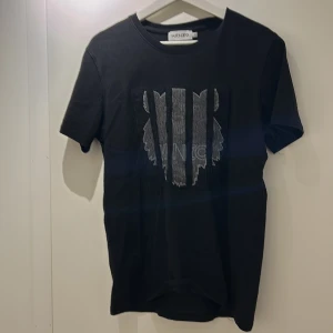 Svart t-shirt från Kenzo - Snygg svart t-shirt från Kenzo med ett coolt broderat mönster på framsidan. Perfekt för en stilren look. Kortärmad och i mjukt material.