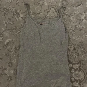 Grå linnetopp från Anna Field - Säljer en stilren grå linnetopp från Anna Field. Perfekt för varma dagar med sin enkla design och smala axelband. Passar utmärkt till både jeans och kjol.