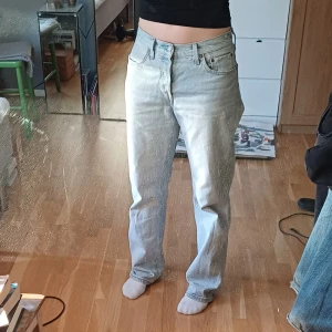 Ljusblå jeans från Levi's - Säljer ett par ljusblå Levi's jeans med klassisk femficksdesign och knappgylf. De har en straight passform och är perfekta för en avslappnad stil. Levi's logga syns på bakfickan.