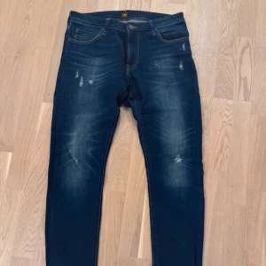 Mörkblå jeansbyxor - Snygga mörkblå jeans med lätt slitna detaljer och klassisk femficksdesign. Perfekta för en avslappnad stil. Midwaist passform och tillverkade i Bangladesh.