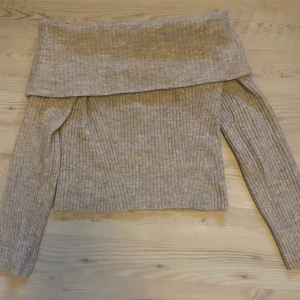 Beige/ grå ribbad offshoulder-tröja från H&M - Säljer en snygg beige ribbad offshoulder-tröja från H&M. Tröjan har långa ärmar och en bred krage som kan bäras nedvikt för en stilren look. Perfekt för kyligare dagar och ger en trendig touch till din outfit. Priser går att diskuteras💗