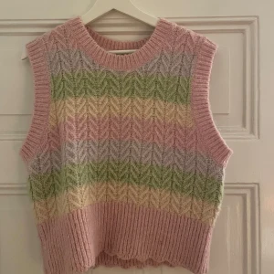 Flerfärgad stickad väst - Säljer en mysig stickad väst i flera färger, inklusive rosa, grön och gul. Västen har ett fint mönster och ribbad nederkant. Perfekt för lager-på-lager under hösten. Storleken är L men sitter som en S på mig som vanligtvis har XS eller S. 