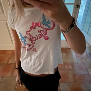 Vit t-shirt från Juicy Couture - Säljer en vit t-shirt från Juicy Couture med ett färgglatt tryck av blå fåglar och rosa text. Den har inga skador eller fläckar, är storlek 14 men passar xs/s