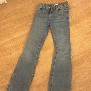 Blå jeans från Gina Tricot - Snygga blå jeans från Gina Tricot med en klassisk design. De har en normal passform och är perfekta för vardagsbruk. Jeansen har en knapp och dragkedja framtill samt fem fickor.