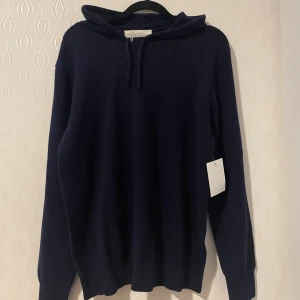 Mörkblå kashmir hoodie från Sayless  - Säljer en lyxig mörkblå hoodie i kashmir från Sayless. Den har en klassisk design med huva och långa ärmar, perfekt för kyliga dagar. Tröjan är mjuk och bekväm, idealisk för både avslappnade och stilrena outfits. 799kr sista pris