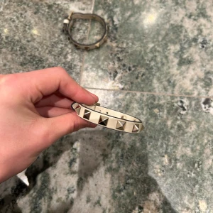 Valentio armband  - Ett beige/vit valentino armband med guldiga nitar! Justerar för alla handleder. Endast armbandet medföljer!
