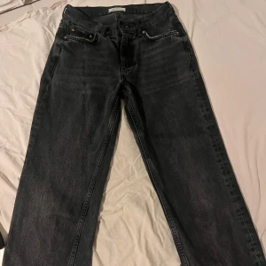 Low straight jeans från Gina tricot  - Snygga svarta jeansbyxor. Från Gina tricot för 500 kr. De har en rak passform och är perfekta för en avslappnad stil. Byxorna har en knapp- och dragkedjestängning framtill. Sann till storlek, 32. Ganska bra skick