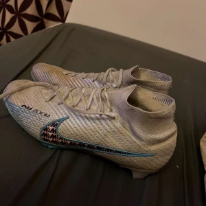 Nike fotbollsskor med mönster. De är elit skor och  kostade för mig 2500kr, det finns inte längre att köpa kolla själv. Ni gärna komma med ett bra bud.  - Snygga fotbollsskor från Nike med ett unikt mönster i svart och blått. Skorna har snörning och en färgglad sula i blått och orange. Perfekta för fotbollsplanen!