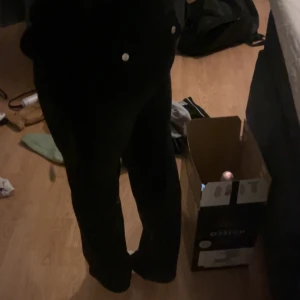 Juicy couture byxor - Snygga svarta byxor med vita knappar baktill. De har en bootcut-stil som ger en trendig look. Perfekta för att matcha med olika toppar och accessoarer. Står stl xss men passar en tjej som har stl s i vanliga fall🤗