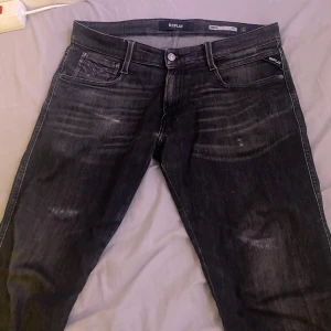 Svarta jeans från Replay - Snygga svarta Replay Anbass jeans i slim fit. De har en klassisk femficksdesign och är tillverkade i ett slitstarkt denimtyg. Perfekta för en stilren look.
