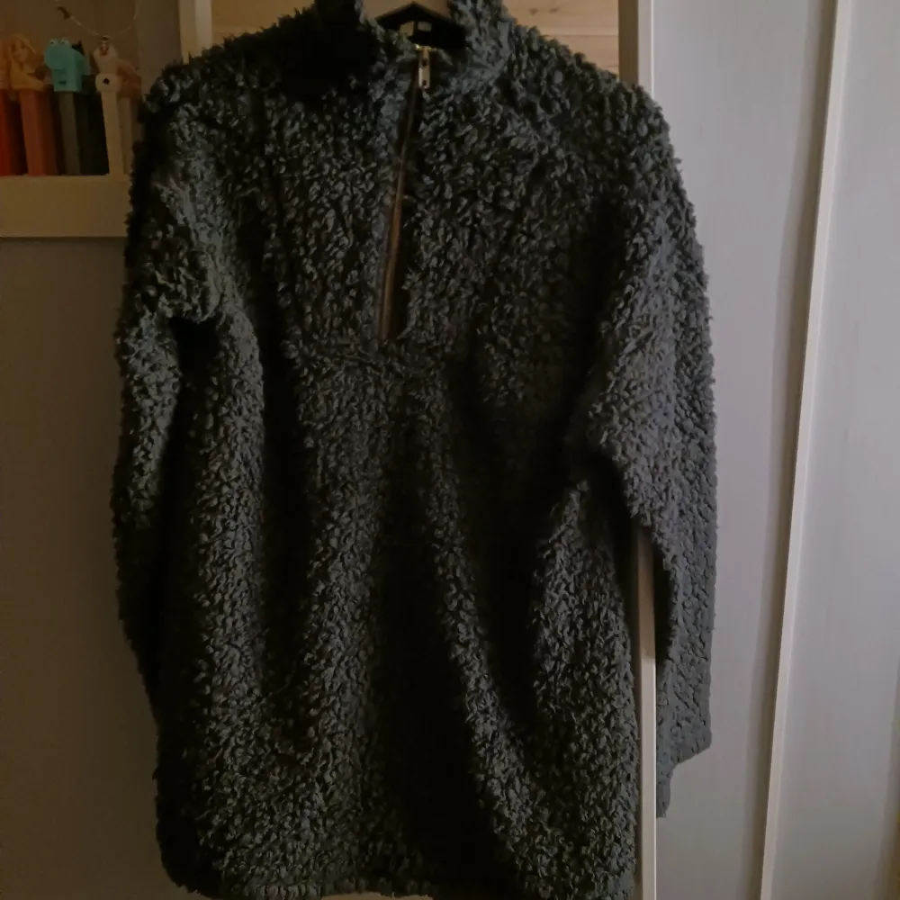 Säljer en mysig mörkgrå fleecejacka från NLY Trend. Jackan har en dragkedja framtill och är perfekt för kyliga dagar. Den är långärmad och har en fluffig textur som ger extra värme och komfort. Som en lång tröja/kort klänning😊. Neuletakit & Villapaidat.