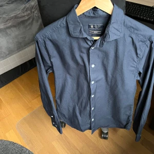 Mörkblå skjorta från Riley - Säljer en stilren marinblå slimfit-skjorta i storlek s. Skjortan är knappt använd och i utmmärkt skick.