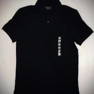 Svart pikétröja från Dressmann - Säljer en klassisk svart pikétröja från Dressmann i storlek M. Tröjan har en stilren design med krage och knappar framtill. Perfekt för både vardag och lite mer uppklädda tillfällen. Passar bra till jeans eller chinos!