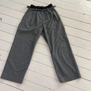 Grå kostym byxor från Zara - Snygga grå kostym byxor från Zara med en loose passform. De har en elastisk midja och ett bälte för extra stil. Perfekta för en avslappnad look. Mycket köna och super snygga med en vit topp!