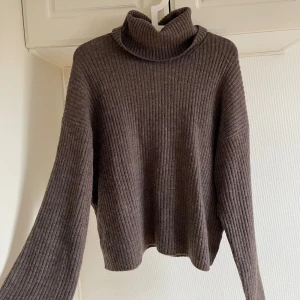 Brun ribbad polotröja M  - Mysig brun polotröja med ribbad struktur. Perfekt för kyliga dagar med sin höga krage och långa ärmar. En stilren och bekväm tröja som passar till många tillfällen.