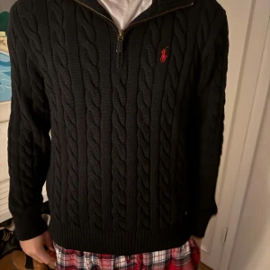 Svart stickad tröja med dragkedja från Ralph Lauren - PRIS KAN DISKUTERAS! Snygg kabelstickad tröja från Ralph Lauren. Nypris: 2800kr. Modellen är 185 och väger 74kg. Använd ett fåtal gånger utan flaws. Mitt pris 900:-