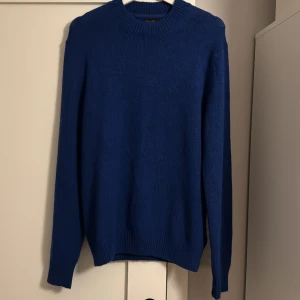 Blå stickad tröja från Massimo dutti - Säljer en stilren blå stickad tröja från Massimo dutti. Tröjan har en klassisk rund hals och långa ärmar med ribbade muddar. Perfekt för kyligare dagar. Aldrig använd då den var för stor för mig! Skick 10/10! 