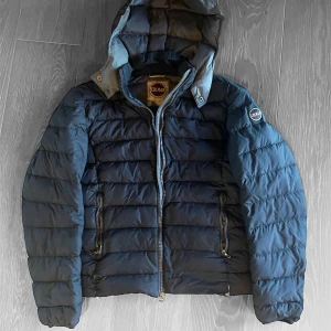 Snygg Blå pufferjacka från Colmar - Snygg och varm mörkblå dunjacka från Colmar med huva och dragkedja. Nypris ligger på cirka 4000kr. Sa Jackan har långa ärmar och två praktiska fickor med dragkedjor framtill. Perfekt för kyliga dagar. Man ska kunna ta jackan till en skräddare och fixa de mindre defekterna ganska  billigt. Priset kan diskuteras