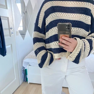Randig stickad tröja från Pull&Bear - Säljer en snygg randig tröja från Pull&Bear i marinblått och beige. Tröjan är stickad med ett luftigt mönster och har långa ärmar. Perfekt för en avslappnad stil.