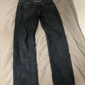 Levis 501 jeans - Säljer ett par klassiska Levis 501 jeans i mörkblå denim. De har en rak passform och är tillverkade i slitstarkt jeansmaterial. Perfekta för en tidlös stil.