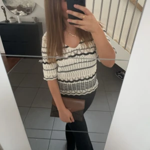 Vit och svart mönstrad topp - Snygg vit topp med svart mönster och v-ringning. Toppen har korta ärmar och ett unikt mönster som ger en stilren look. Perfekt för en trendig outfit.