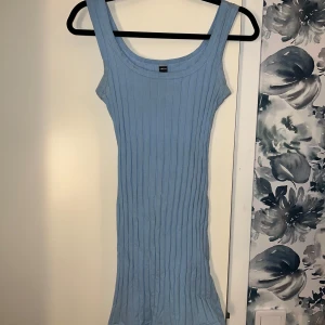 Ljusblå ribbad klänning från Gina Tricot - Snygg ljusblå ribbad klänning från Gina Tricot. Den är ärmlös med en tight passform som framhäver figuren. Perfekt för varma dagar eller sommarens fester. Jätte stretchig i material och mer baby blå i färgen än i bilderna.