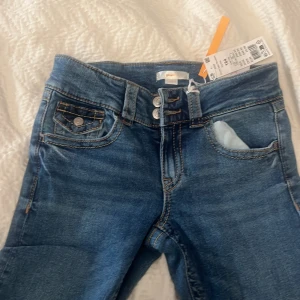Blå jeans från Gina Tricot - Snygga blå jeans från Gina Tricot med klassisk femficksdesign och knappgylf. Dom är nya 