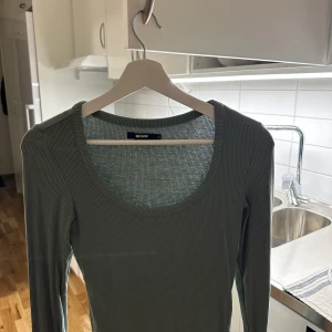 Grön ribbad tröja från Bik Bok - Säljer en stilren grön ribbad tröja från Bik Bok. Tröjan har en rund halsringning och långa ärmar, perfekt för lager-på-lager under kyligare dagar.