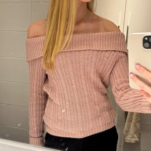Rosa stickad offshoulder tröja - Säljer en snygg rosa offshoulder stickad tröja. Den har långa ärmar och en bred krage som ger en trendig look. Perfekt för kyligare dagar när du vill vara både varm och stilren.