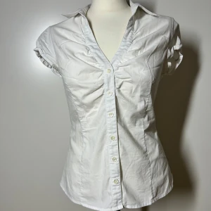 Kortärmad tajt skjorta  - Vit kortärmad figursydd skjorta. Storlek 36. Har även en till tajt skjorta i svart uppe på min plick. Köp sker via köp nu, jag postar inom 24h. Kvar tills markerad såld 