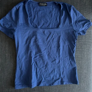 Blå topp från Kappahl - Säljer en blå topp från Kappahl med korta ärmar och fyrkantig halsringning. Perfekt för en avslappnad stil.