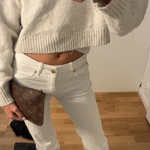 Brun kuvertväska med monogram - Snygg brun kuvertväska med klassiskt monogrammönster. Perfekt för att bära med sig det viktigaste. Väskan har en dragkedja upptill för säker förvaring.