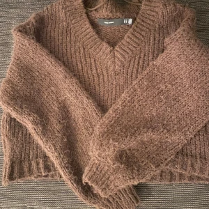 Brun stickad tröja  - Mysig brun stickad tröja med v-ringning. Perfekt för kyliga dagar och fina detaljer vid ärmslut. Lite kortare i modellen. Väldigt varm och skönt material. Från veromoda. 