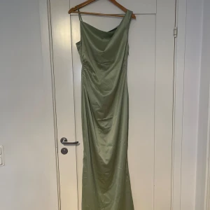Grön långklänning  - Verkar främst som intressekoll i nuläget!Adoore klänning, ”Almeria dress”. Elegant grön långklänning med smala axelband och draperad detalj på sidan. Perfekt för en stilren look med en mjuk och glansig finish. Klänningen är i strl 40 (M).   Klänningen är aldrig använd,  endast testad. Lapp finns kvar. Ny pris - 1595 kr 