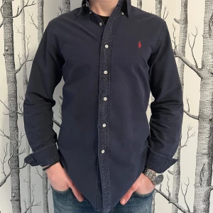 Ralph Lauren Skjorta - Marinblå Ralph Lauren-skjorta i bomull | Skick: 7/10 (endast små slitningar i manschetter och krage) | Storlek: M | Pris: 399 kr | Modell: 173 cm och 63 kilo | Hör av dig vid frågor och funderingar! 🌟