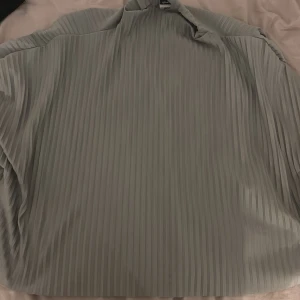 En grön blus från Gina Tricot - Detta är en grön blus med halv öppen rygg med två snören man kan knyta ihop