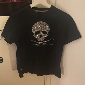 Svart t-shirt med dödskallemotiv - Cool svart t-shirt med ett glittrigt dödskallemotiv på framsidan, några av stenarna har lossnat men det märks knappt