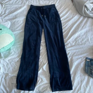 Mörkblå byxor från Juicy Couture - Säljer ett par mörkblå mjukisbyxor från Juicy Couture i storlek S. Byxorna har en bekväm passform med dragsko i midjan och fickor både fram och bak. Perfekta för en avslappnad stil. Pris kan diskuteras!!!