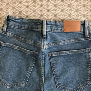 Blå jeans från Ginatricot  - Snygga blå jeans från Ginatricot med klassisk femficksdesign och knappgylf. Perfekta för en avslappnad stil. De har en slim passform och är tillverkade i slitstarkt denim.